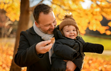 Joyful dad and his little baby. daddy and child have fun, laugh and enjoy nature outdoors at autumn park.の写真素材
