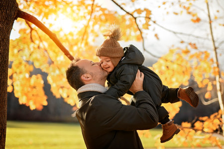 Joyful dad and his little baby. daddy and child have fun, laugh and enjoy nature outdoors at autumn park.の写真素材