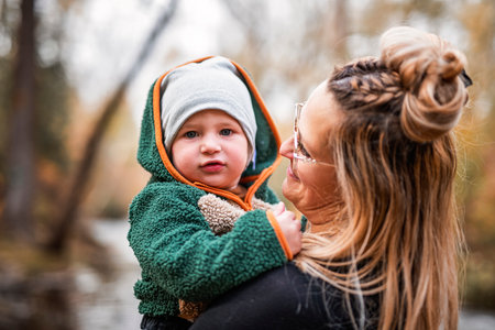 Joyful mom and her little baby. mother and child have fun, laugh and enjoy nature outdoors at autumn park.の写真素材