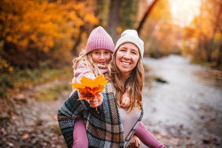 Joyful mom and her little child girl. mother and child have fun outdoors at autumn park.の写真素材