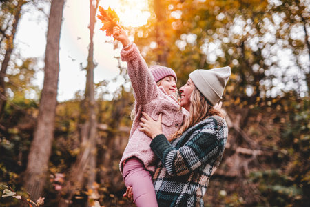 Joyful mom and his little child girl. mother and child have fun outdoors at autumn park.