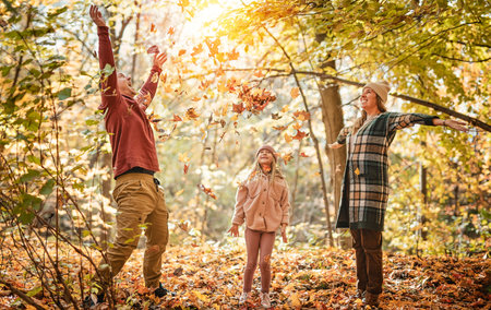 Joyful family and their little child girl have fun outdoors at autumn park.の写真素材
