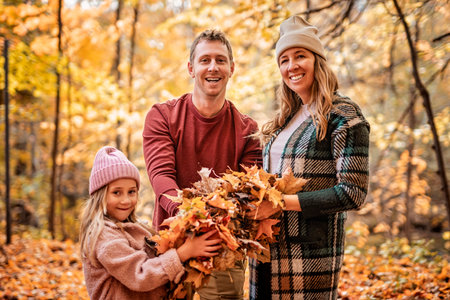 Joyful family and his little child girl have fun outdoors at autumn park.の写真素材