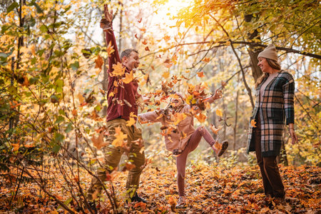 Joyful family and his little child girl have fun outdoors at autumn park.の写真素材