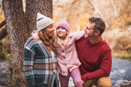 Joyful family and his little child girl have fun outdoors at autumn park.
