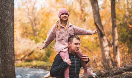 Joyful dad and his little daughter. daddy and child have fun, laugh and enjoy nature outdoors at autumn park.の写真素材