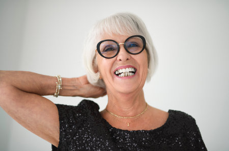 Portrait of elderly woman in eyeglasses over grey background.
