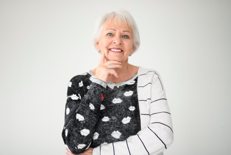 Portrait of elderly woman over grey background.