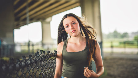 Teen girl posing outdoors wearing urban clothes close to a fenceの写真素材