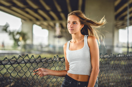 Teen girl posing outdoors wearing urban clothes close to a fenceの写真素材
