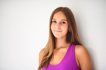 portrait of a 14 years old teen girl close to a white wall with colored shirtの写真素材