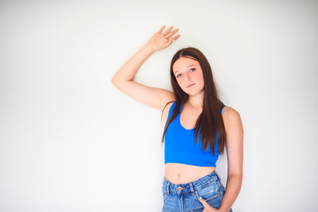 portrait of a 14 years old teen girl close to a white wall with colored shirtの写真素材