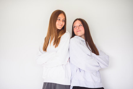 Two best girlfriends together on white studio wearing hoodiesの写真素材