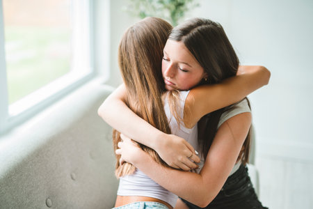 Two best girls consoling together sit on sofaの写真素材