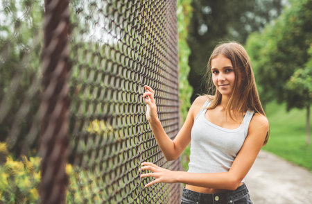Teen girl posing outdoors wearing urban clothes close to a fenceの写真素材
