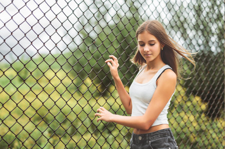Teen girl posing outdoors wearing urban clothes close to a fenceの写真素材