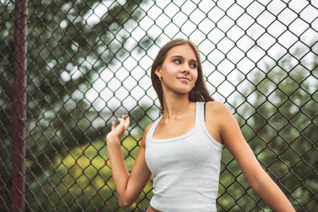 Teen girl posing outdoors wearing urban clothes close to a fenceの写真素材