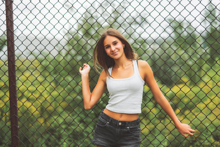 Teen girl posing outdoors wearing urban clothes close to a fenceの写真素材