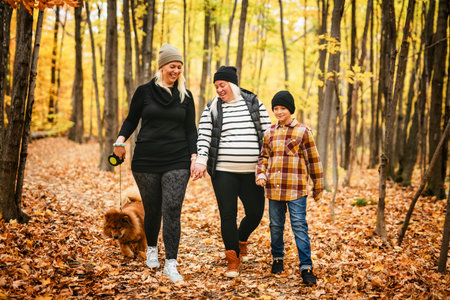 Joyful pregnant family. Lesbian couple and child have fun on nature outdoors at autumn park.の写真素材