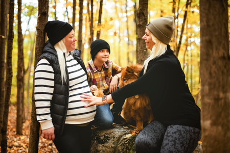 Joyful pregnant family. Lesbian couple and child have fun on nature outdoors at autumn park.