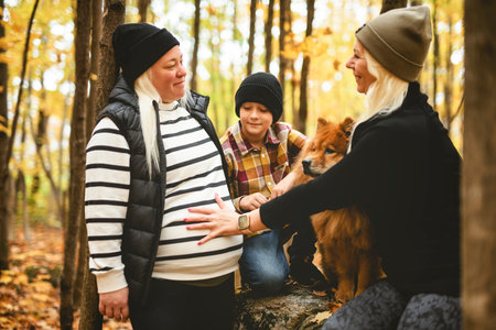 Joyful pregnant family. Couple and child have fun on nature outdoors at autumn park.の写真素材