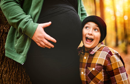 Joyful pregnant mother and his little boy. mother and child have fun on nature outdoors at autumn park.の写真素材