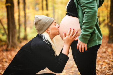 Lesbian couple having fun on autumn forest with futur newborn child on woman belly.の写真素材