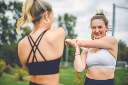 Healthy two sporty young girls jogging and stretching outdoorsの写真素材