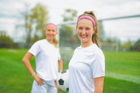 two soccer player friends with a football in a sport uniform wearing in whiteの写真素材