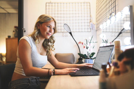 Single student browsing content online in a laptop sitting in a desk in her bedroom in a house interiorの写真素材