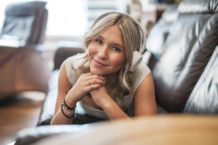 teen listening to music with wireless headphones sitting on a couchの写真素材