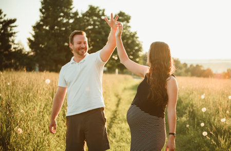pregnant woman at sunset with her boyfriend dancing. Concept of pregnancy, maternity, expectation...