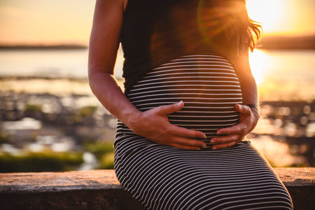 Silhouette of a pregnant woman at sunset. Concept of pregnancy, maternity, expectation for baby birth.の写真素材