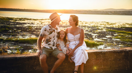 happy child girl and mother and father are playing on border to oceanの写真素材