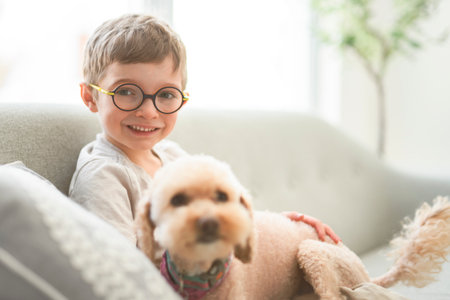 portrait of handsome little boy in glasses sit on sofa with dog