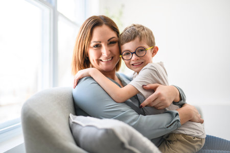 Portrait of boy smiling at camera with his mother at homeの写真素材