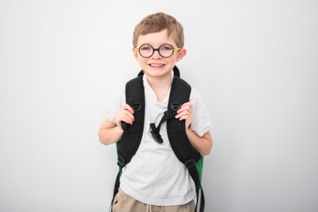 portrait of handsome little student boy in glasses isolated on gray background