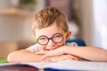 homework and school concept - smiling student boy with book writing to notebook at homeの写真素材