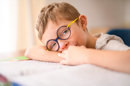 homework and school concept - tired student boy with book writing to notebook at homeの写真素材
