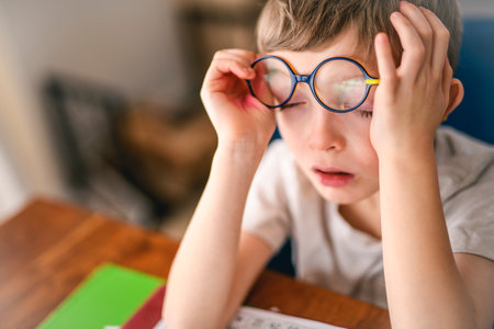 homework and school concept - tired student boy with book writing to notebook at home
