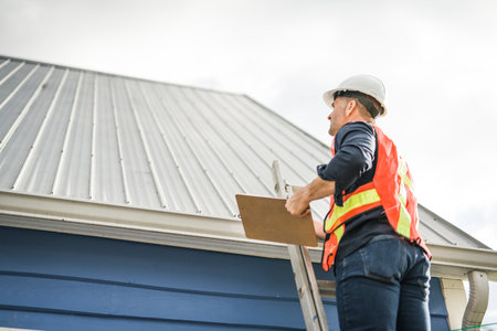 man with hard hat standing on steps inspecting house roof