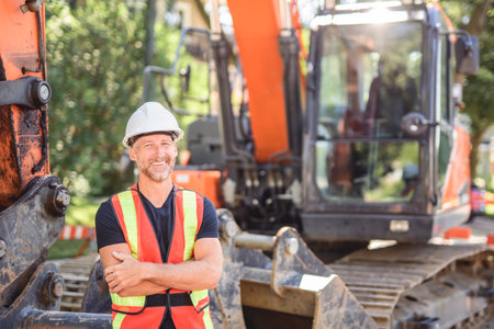 caucasian engineer with white helmet at work and having a mechanical shovel on the backの写真素材