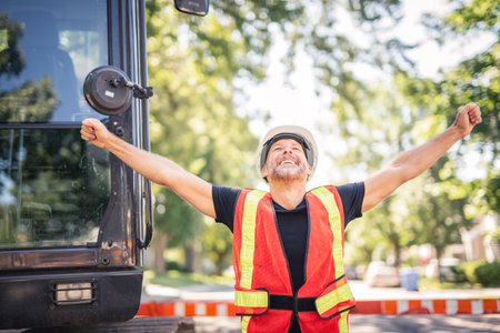 caucasian engineer with white helmet at work and having a mechanical shovel on the backの写真素材
