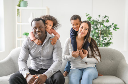 family with boy and girl child posing on photo shooting, sitting on couch
