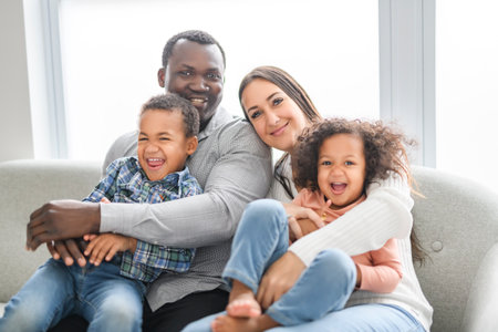 family with boy and girl child posing on photo shooting, sitting on couch