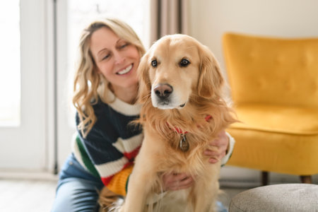Portrait of woman with healthy golden retriever dog indoors in at home.の写真素材
