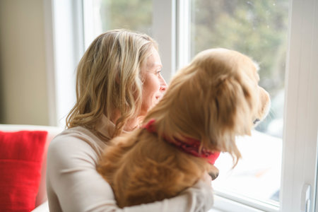 Portrait of woman with healthy golden retriever dog indoors in at home.の写真素材