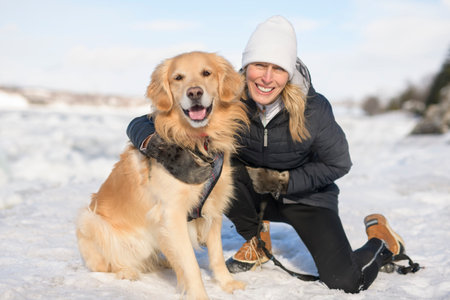 Portrait of woman with healthy golden retriever dog outside in winter seasonの写真素材
