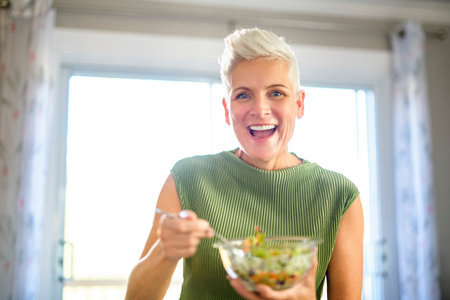 Mature smiling woman eating salad.の写真素材