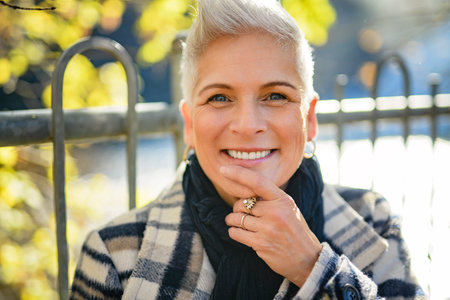 Mature woman in autumn forest, dressed in cozy fall attire, Reflection and connection with nature, wellnessの写真素材